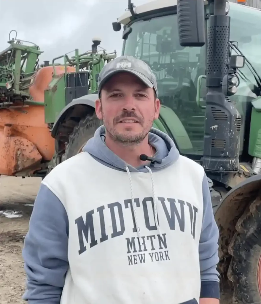 Un jeune agriculteur se tient devant son tracteur