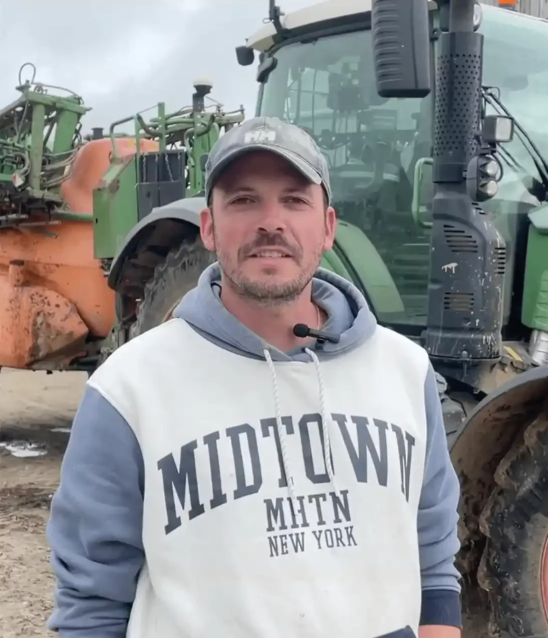 Un jeune agriculteur se tient devant son tracteur